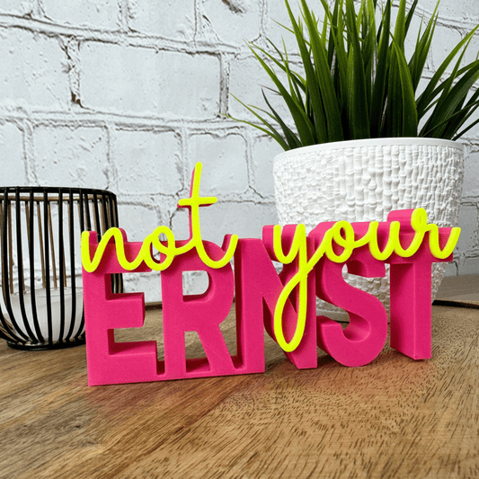 3D Schriftzug „not your ernst“ aus PLA in Pink mit gelber Schrift, stehende Deko auf Holzuntergrund