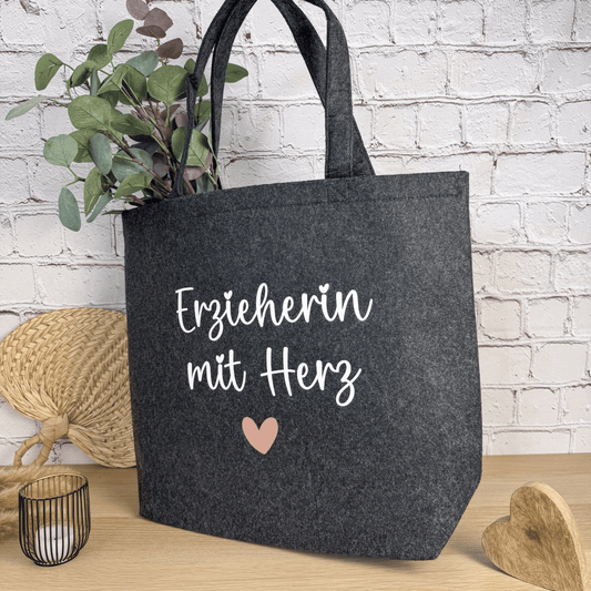 Perspektivansicht der anthrazitfarbenen Filztasche „Erzieherin mit Herz“, dekorativ mit Pflanze und Holzelement