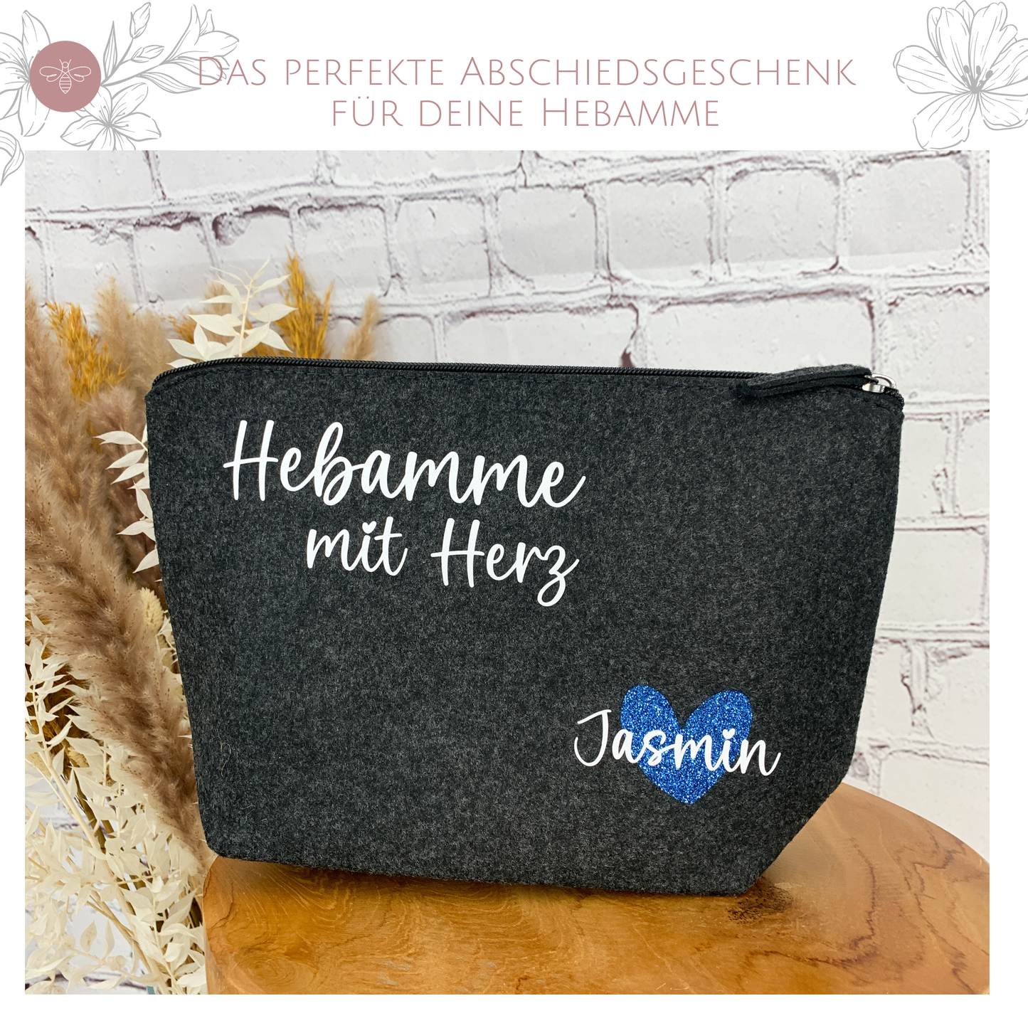 Schrägansicht der grauen Filztasche "Hebamme mit Herz" mit personalisiertem Namen "Jasmin" und einem funkelnden blauen Herz.