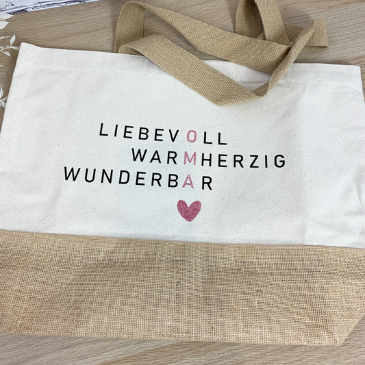 Jutetasche flach liegend mit Aufschrift 'Oma liebevoll warmherzig wunderbar' in Glitzerschrift – ein liebevolles Geschenk für die beste Oma
