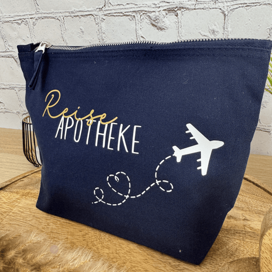 Detailaufnahme der Reiseapotheke-Tasche in navyblau mit gold-weißer Schrift und Flugzeuggestaltung