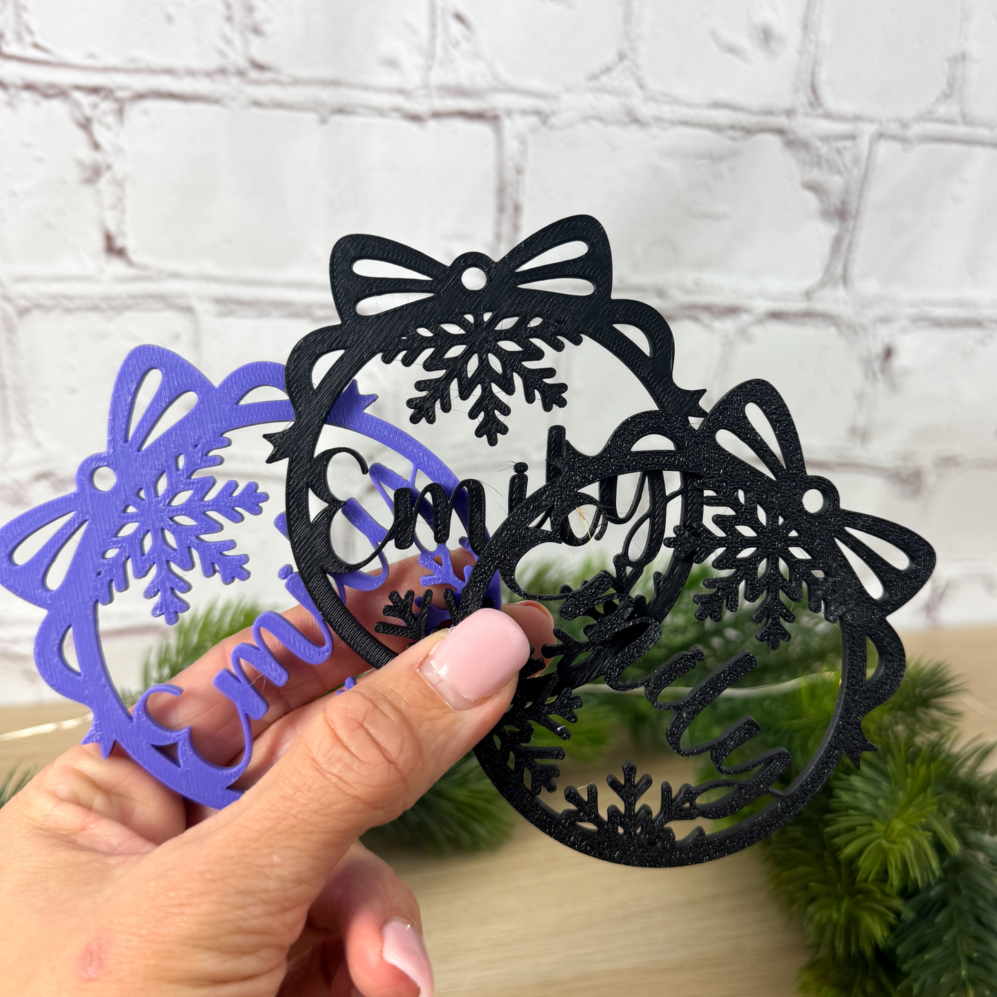 Hand hält drei 3D-Weihnachtsbaumanhänger in Schwarz und Lila – Schneeflocke mit Schleife – Weihnachtsdeko