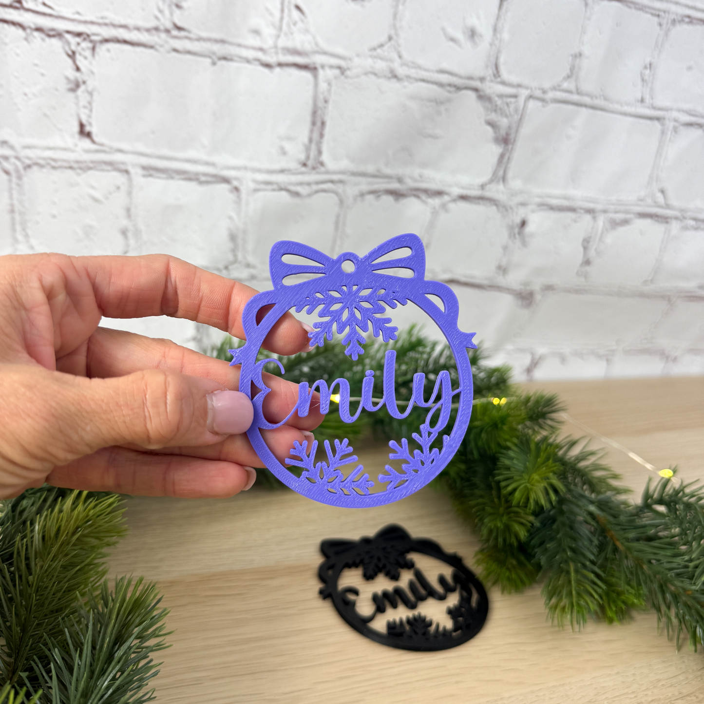 Lila 3D-Weihnachtsanhänger mit Name Emily – Schneeflocke und Schleife – in Hand gehalten