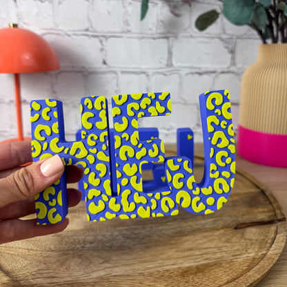 3D-Schriftzugs HEJ in Blau mit gelbem Leopardenmuster, Nahaufnahme in der Hand