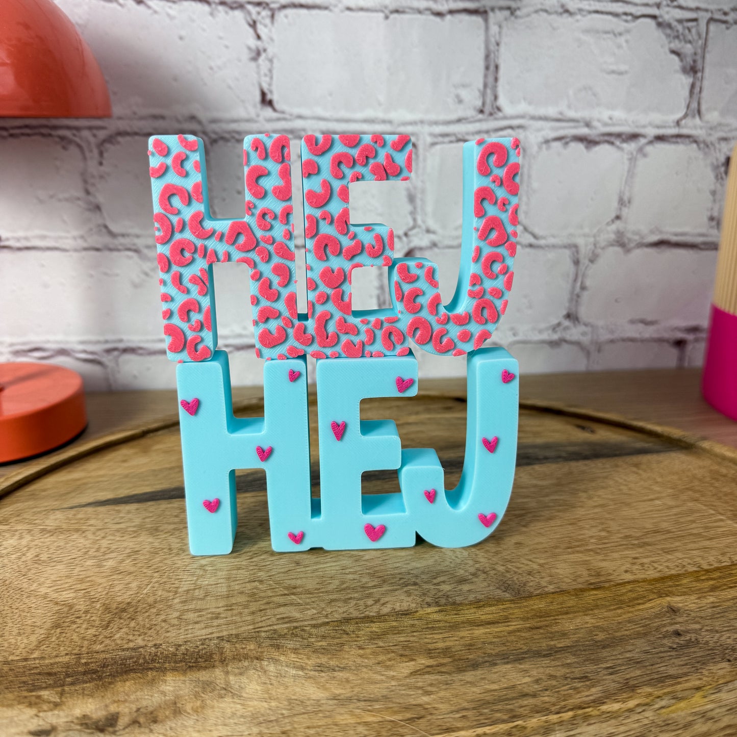 3D-Schriftzug HEJ in Türkis mit pinkem Leopardenmuster und pinken Herzchen auf Holztablett