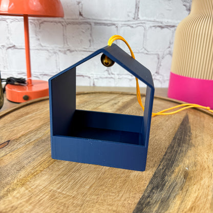 Einzelne 3D-gedruckte Vogelfutterstation in Dunkelblau mit gelbem Band und goldener Holzperle