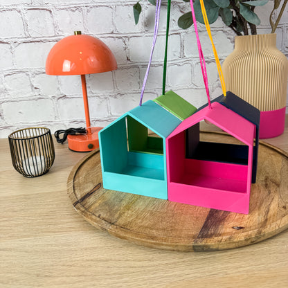 3D-gedruckte Vogelfutterstationen in Türkis, Grün und Pink mit bunten Aufhängebändern von oben