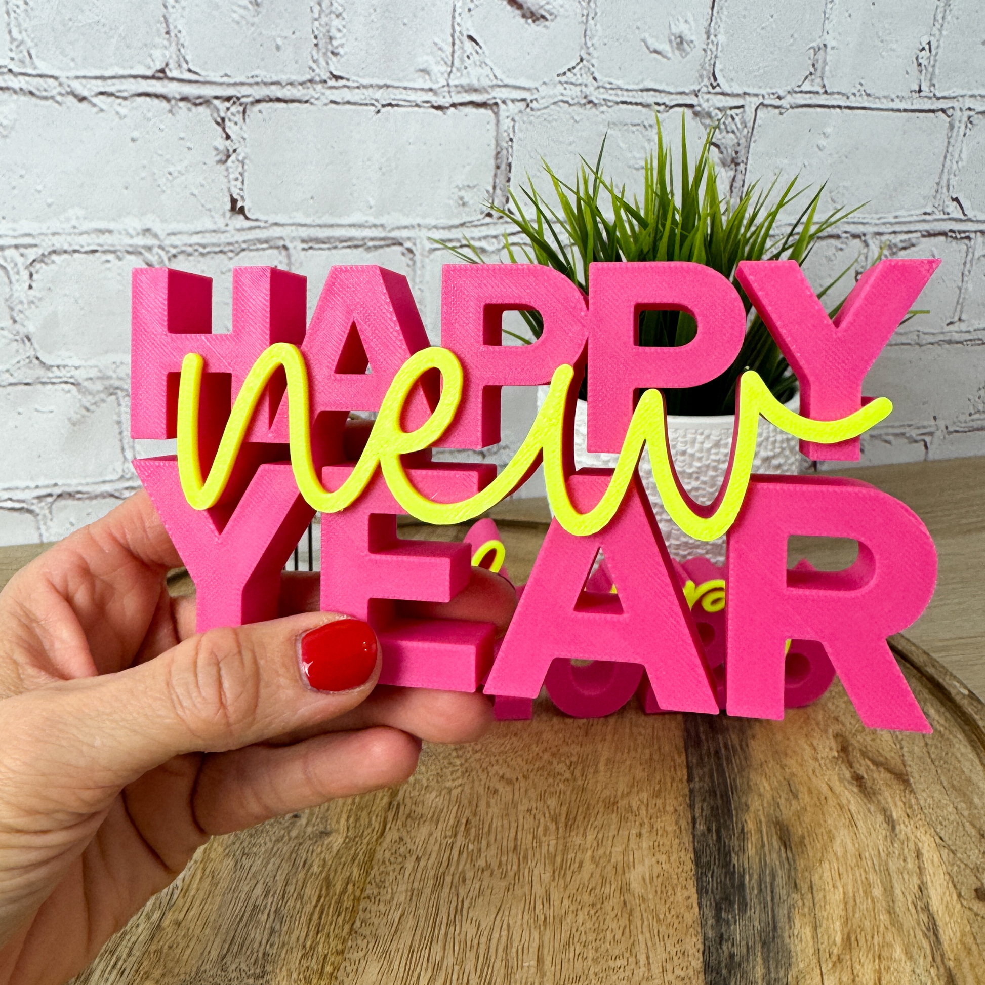 3D Schriftzug „happy new year“ in der Hand gehalten, farbenfrohe Silvester-Deko aus PLA