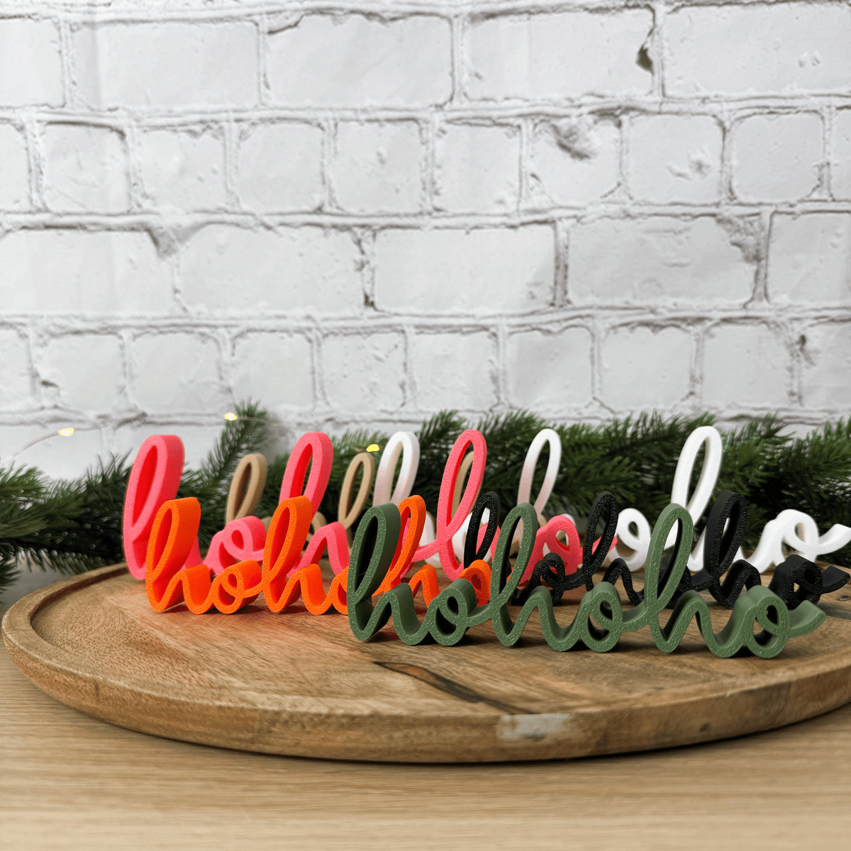 Mehrere hohoho 3D-Schriftzüge in Rosa, Orange, Dunkelgrün, Weiß, Beige und Schwarz nebeneinander