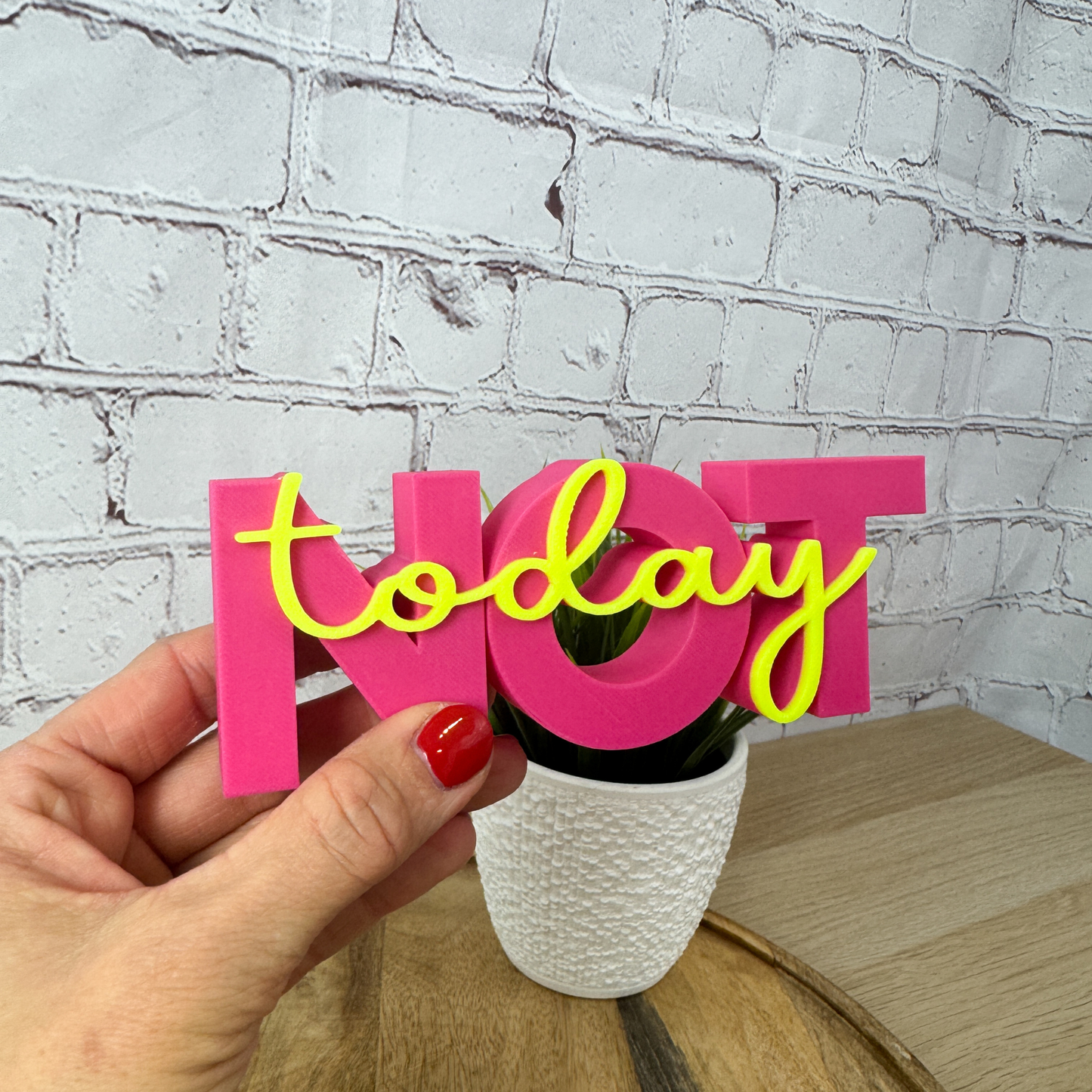 3D Schriftzug „NOT“ aus PLA in Pink mit gelbem Schriftzug „today“, in der Hand gehalten vor hellem Hintergrund