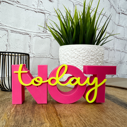 3D Schriftzug „NOT“ in Pink mit gelbem Schriftzug „today“, leicht seitliche Perspektive auf Holzuntergrund