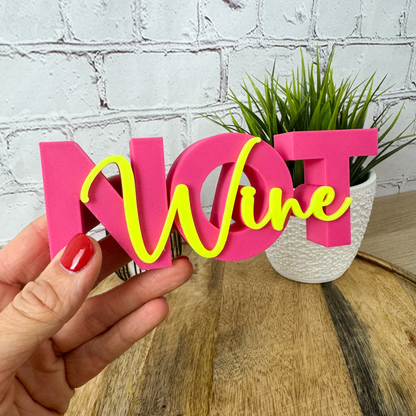 3D Deko-Schriftzug „Wine not“ in Pink mit gelbem Schriftzug, perfekt als Geburtstagsgeschenk, Detailaufnahme in der Hand