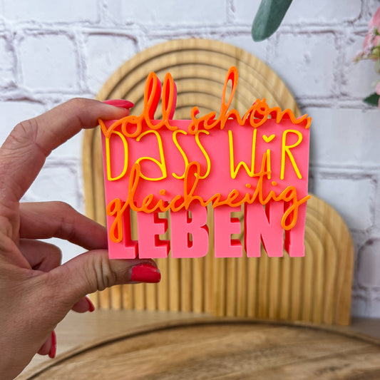3D Spruch „Voll schön, dass wir gleichzeitig leben“ in Rosa, Gelb und Orange, Nahaufnahme in der Hand