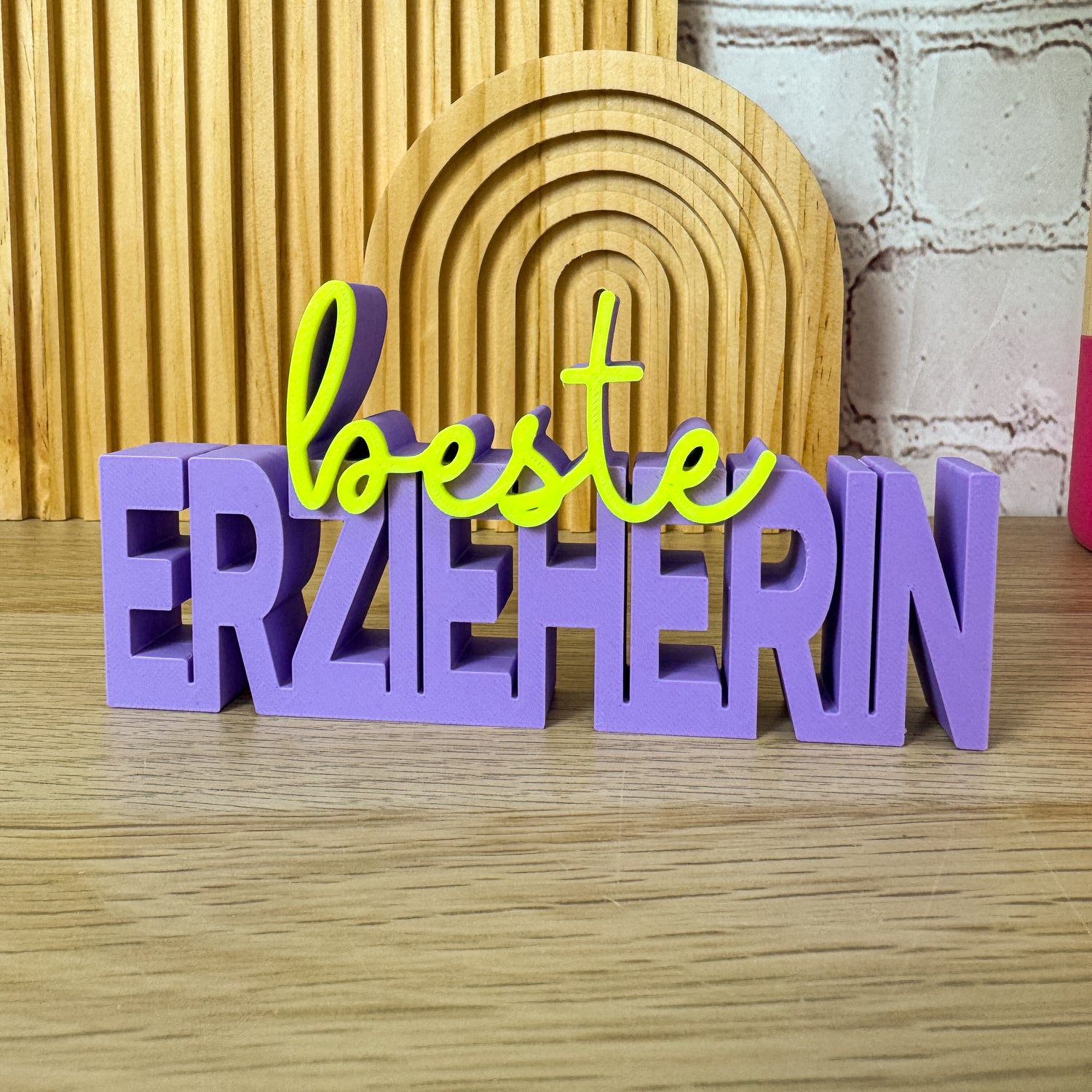 3D-Schriftzug »beste Erzieherin« in Lila und Neon-Gelb stehend auf Holztisch als Geschenk Kita-Abschied