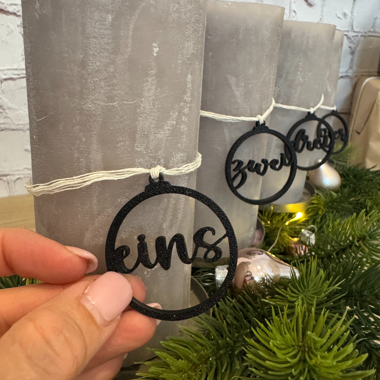Nahaufnahme eines schwarzen Zahlenanhängers „eins“ am Adventskranz – handgefertigte Deko aus PLA für Adventskerzen