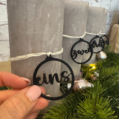 Nahaufnahme eines schwarzen Zahlenanhängers „eins“ am Adventskranz – handgefertigte Deko aus PLA für Adventskerzen