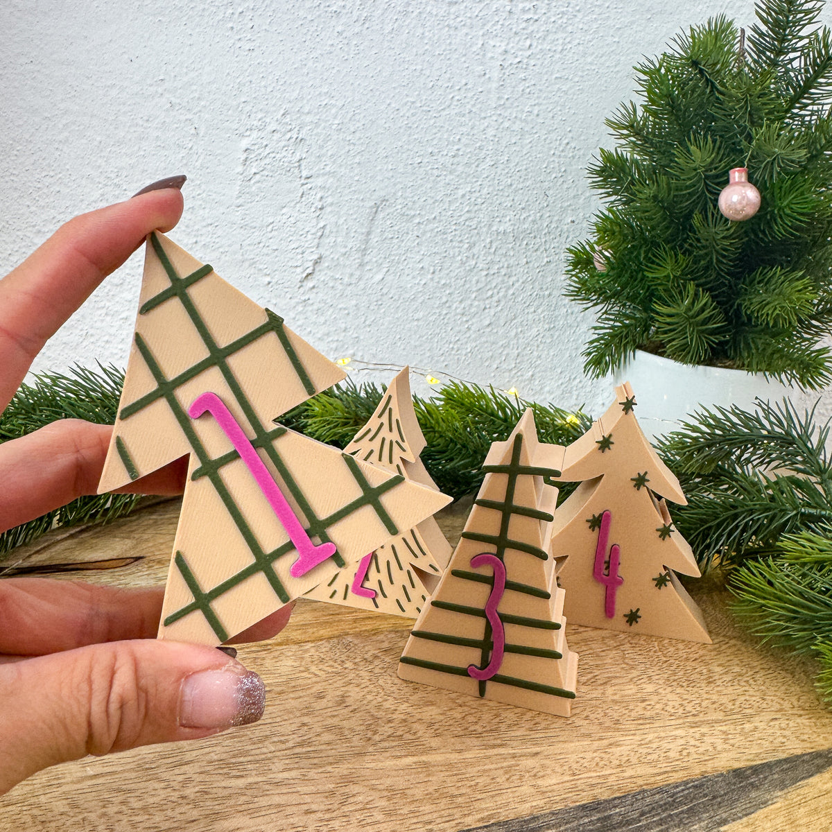 Adventszahl 1 in Tannenbaumform in einer Hand gehalten, weitere Zahlen im Hintergrund