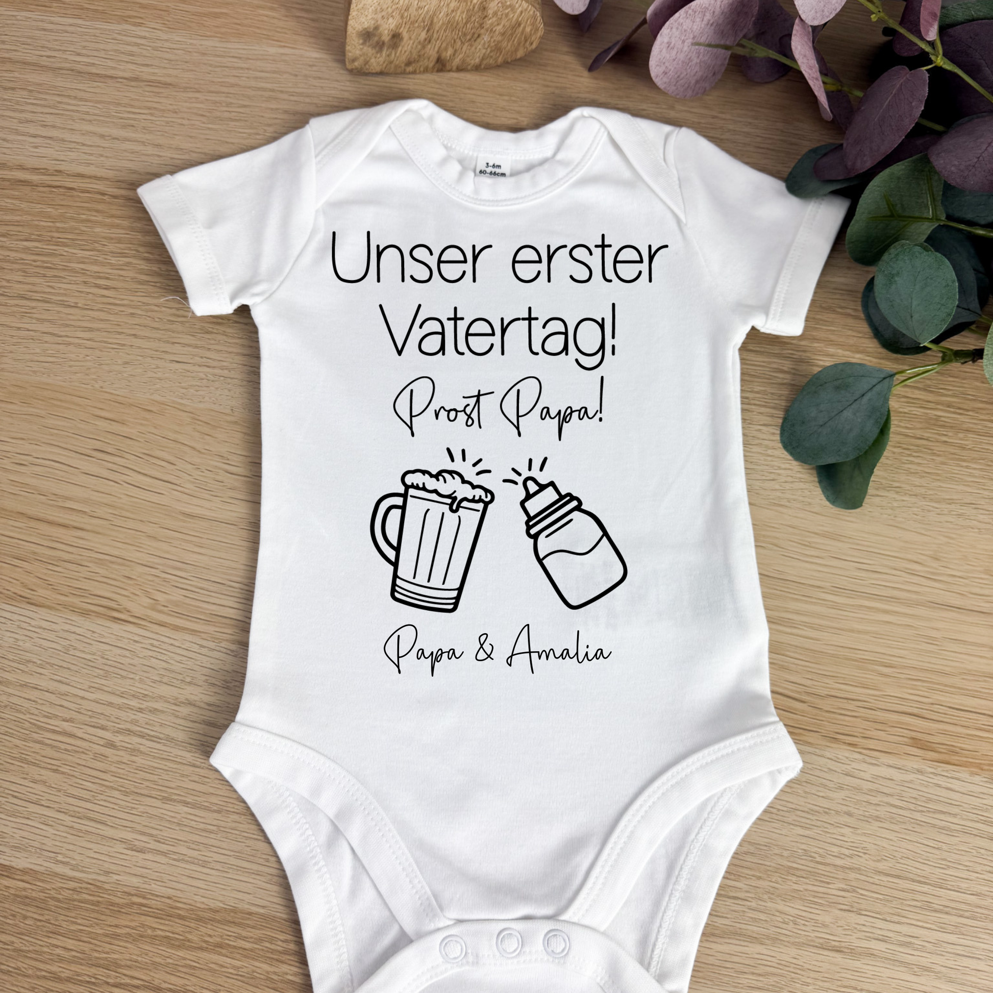 Babybody in Weiß mit "Unser erster Vatertag"-Aufdruck, stilvoll in einem Babykorb dekoriert – eine wunderschöne Geschenkidee.