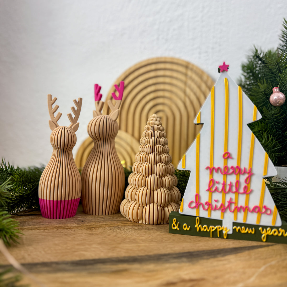 Christmas Schriftzug als Weihnachtsdeko neben Rentierfiguren und Deko-Tannenbaum