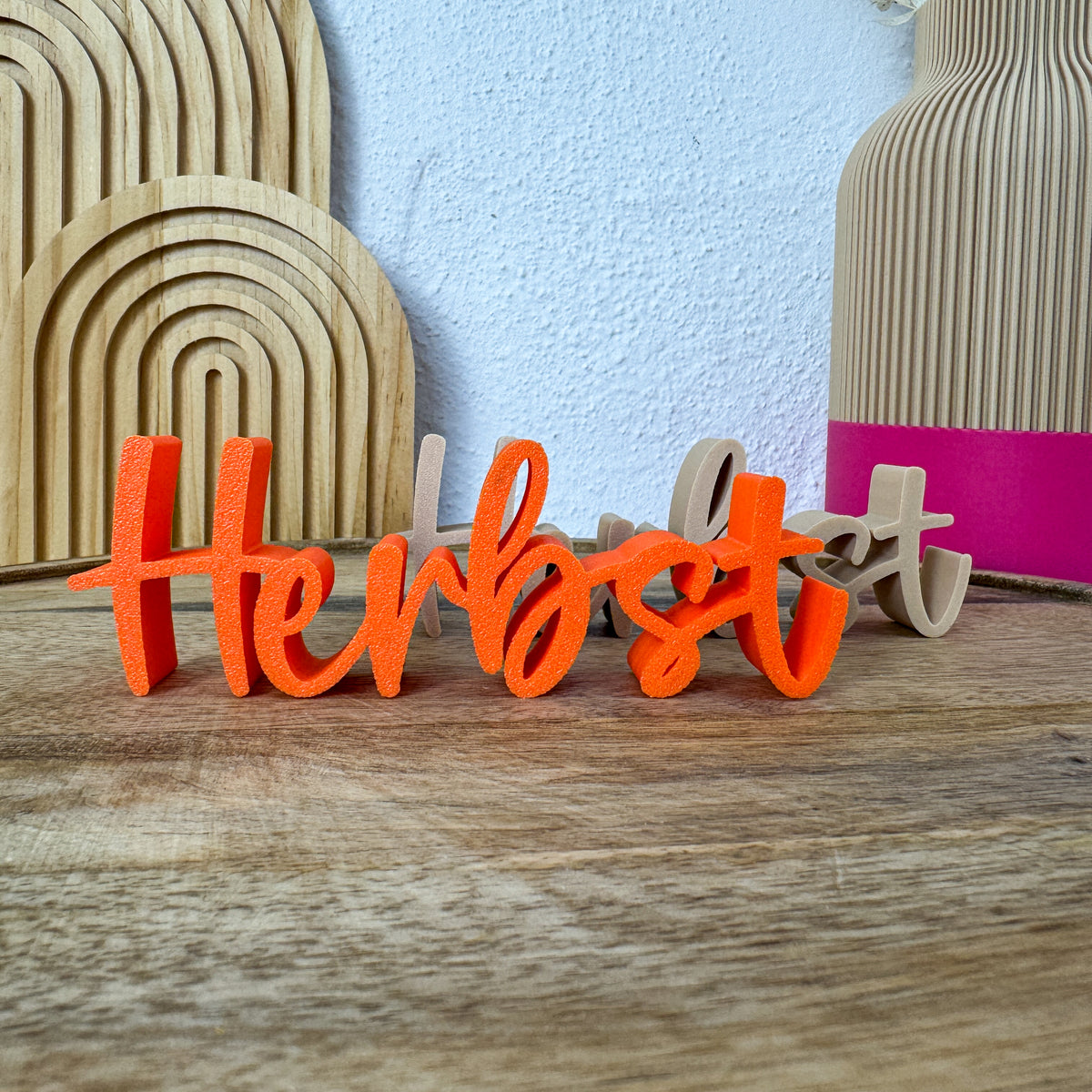 3D-Schriftzug Herbst in Orange, dahinter ein zweites Exemplar in Beige, als Herbstdeko auf Holz