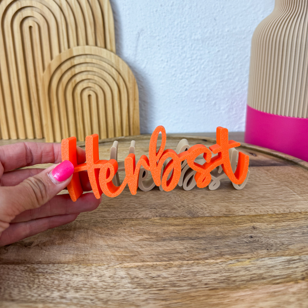 Herbst Schriftzug in Orange seitlich in der Hand, zeigt die 2 cm tiefe 3D-Form des Buchstabenzugs