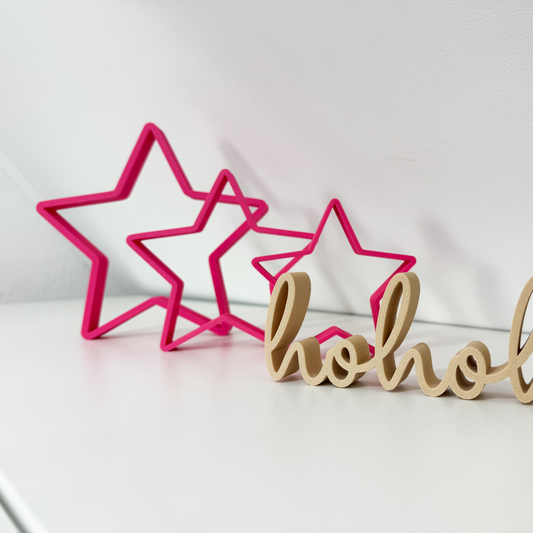 Festliche Kombination aus Magenta 3D Sternen und hohoho Deko-Schriftzug auf weißer Fläche