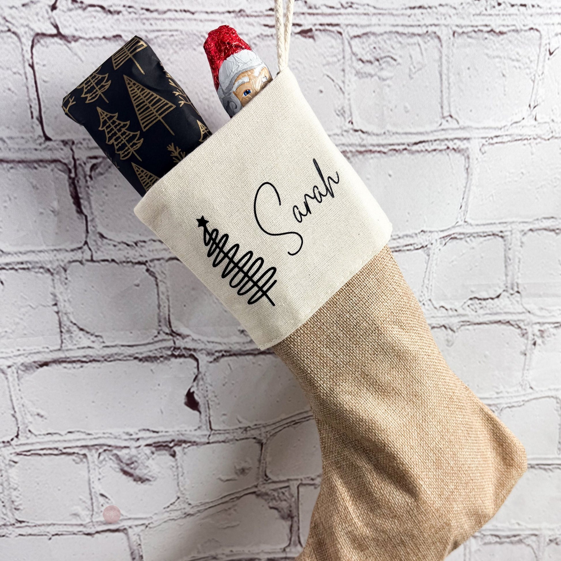 Nikolaussocke mit Name Sarah an einer Backsteinwand aufgehängt, gefüllt mit Nikolaus und Geschenk – festliche Dekoidee.
