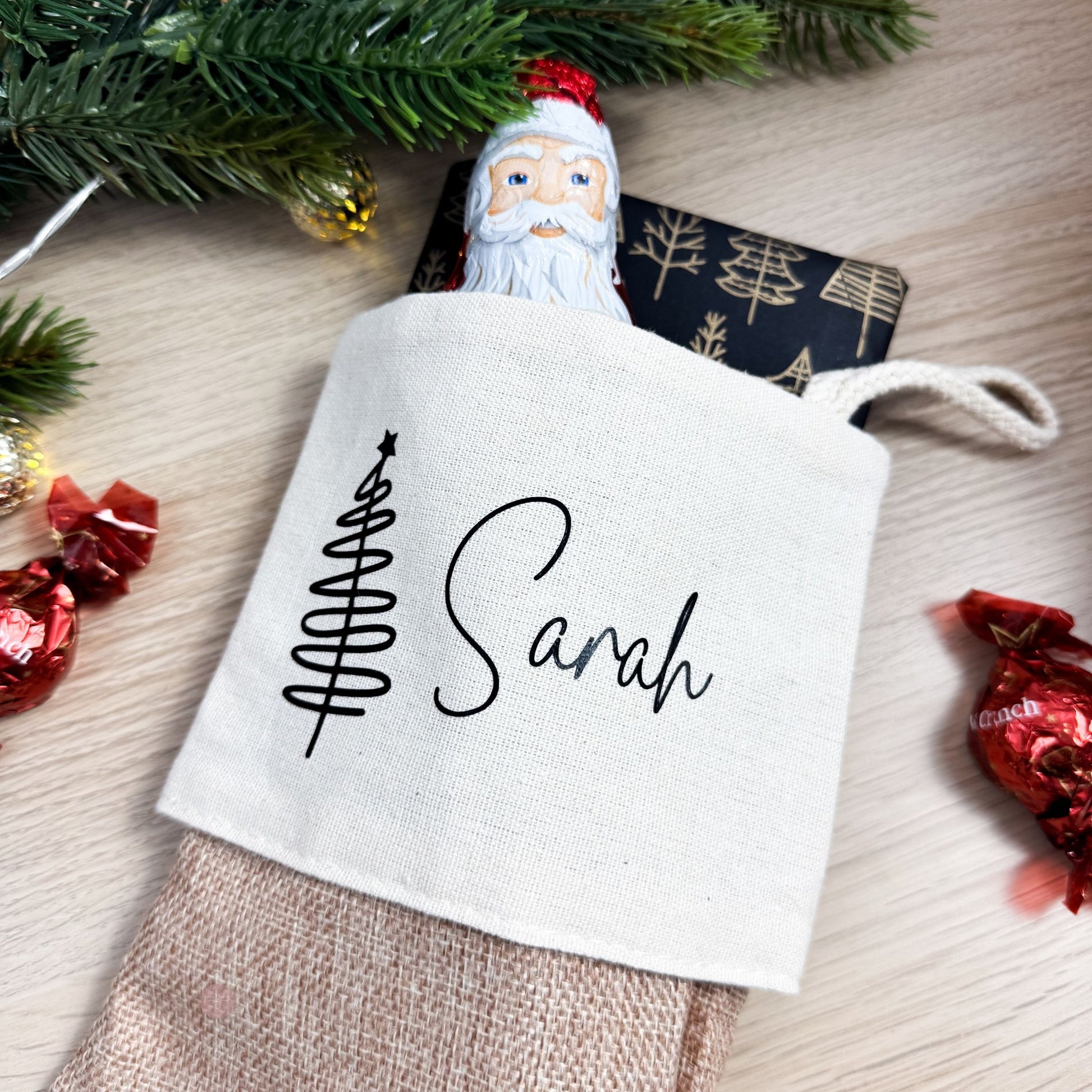 Personalisierter Nikolausstrumpf mit Namen Sarah, gefüllt mit Schokolade und Geschenk, auf weihnachtlich dekoriertem Tisch.