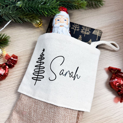 Personalisierter Nikolausstrumpf mit Namen Sarah, gefüllt mit Schokolade und Geschenk, auf weihnachtlich dekoriertem Tisch.