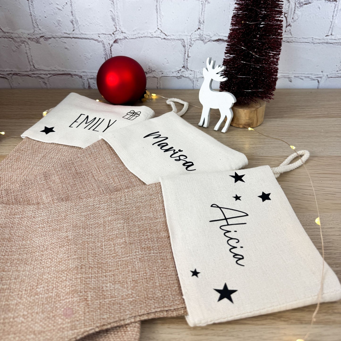 Nikolaussocken personalisiert mit verschiedenen Namen wie "Emily" und "Alicia", auf einem Tisch mit weihnachtlicher Deko.