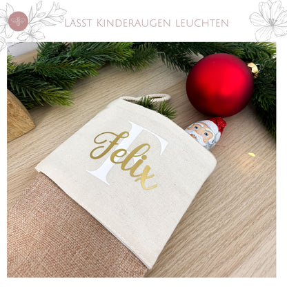 Der personalisierte Nikolausstrumpf „Felix“ gefüllt mit einem Schokoladen-Weihnachtsmann, umringt von Tannenbaumschmuck.