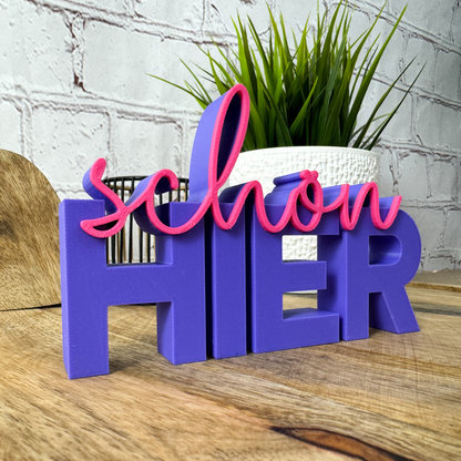 Deko-Schriftzug „schön hier“ in Lila mit pinker Schrift – moderne Farbkombination für Wohnung oder Büro