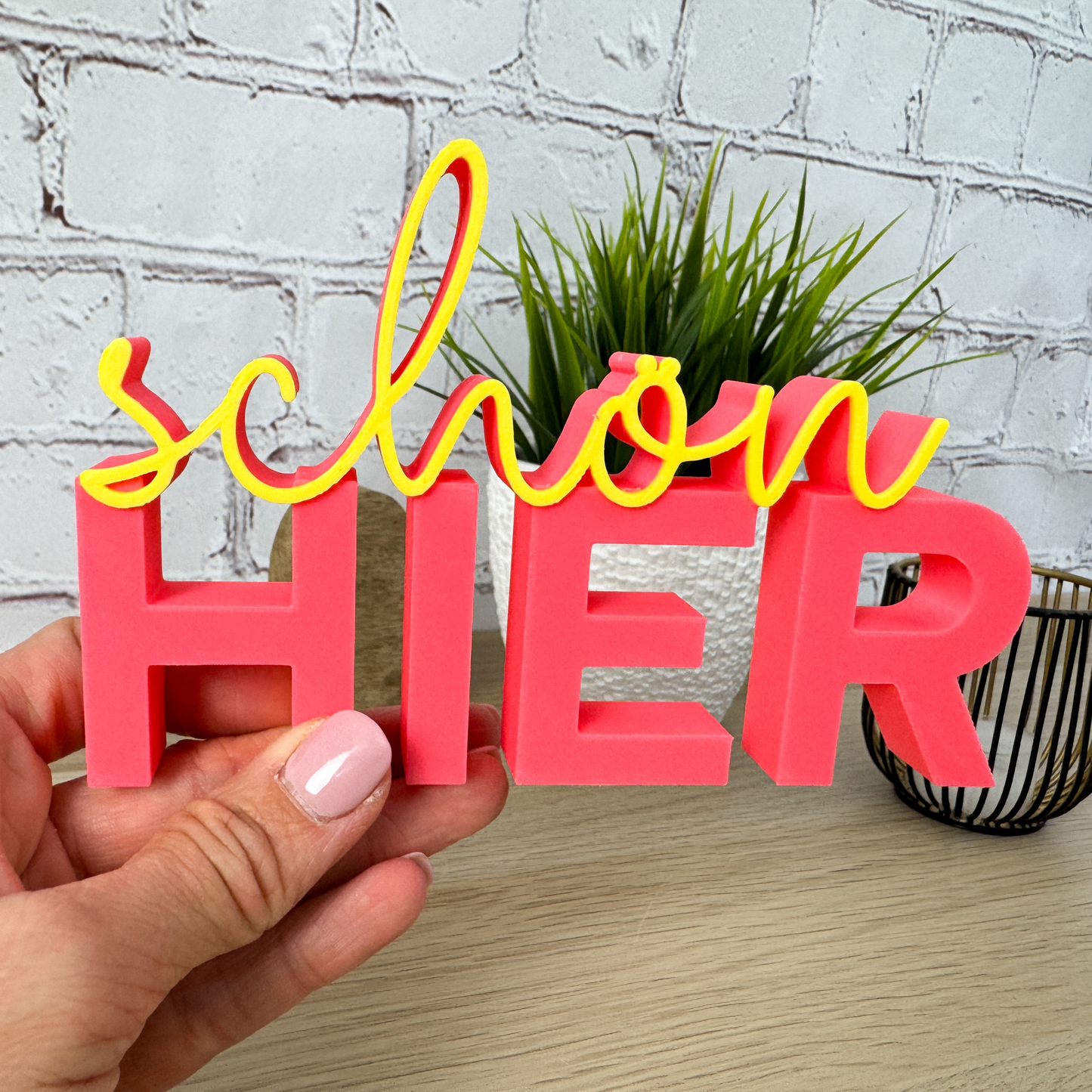 3D Schriftzug „schön hier“ in rosa  und Gelb in der Hand – kreative Geschenkidee für neue Wohnung