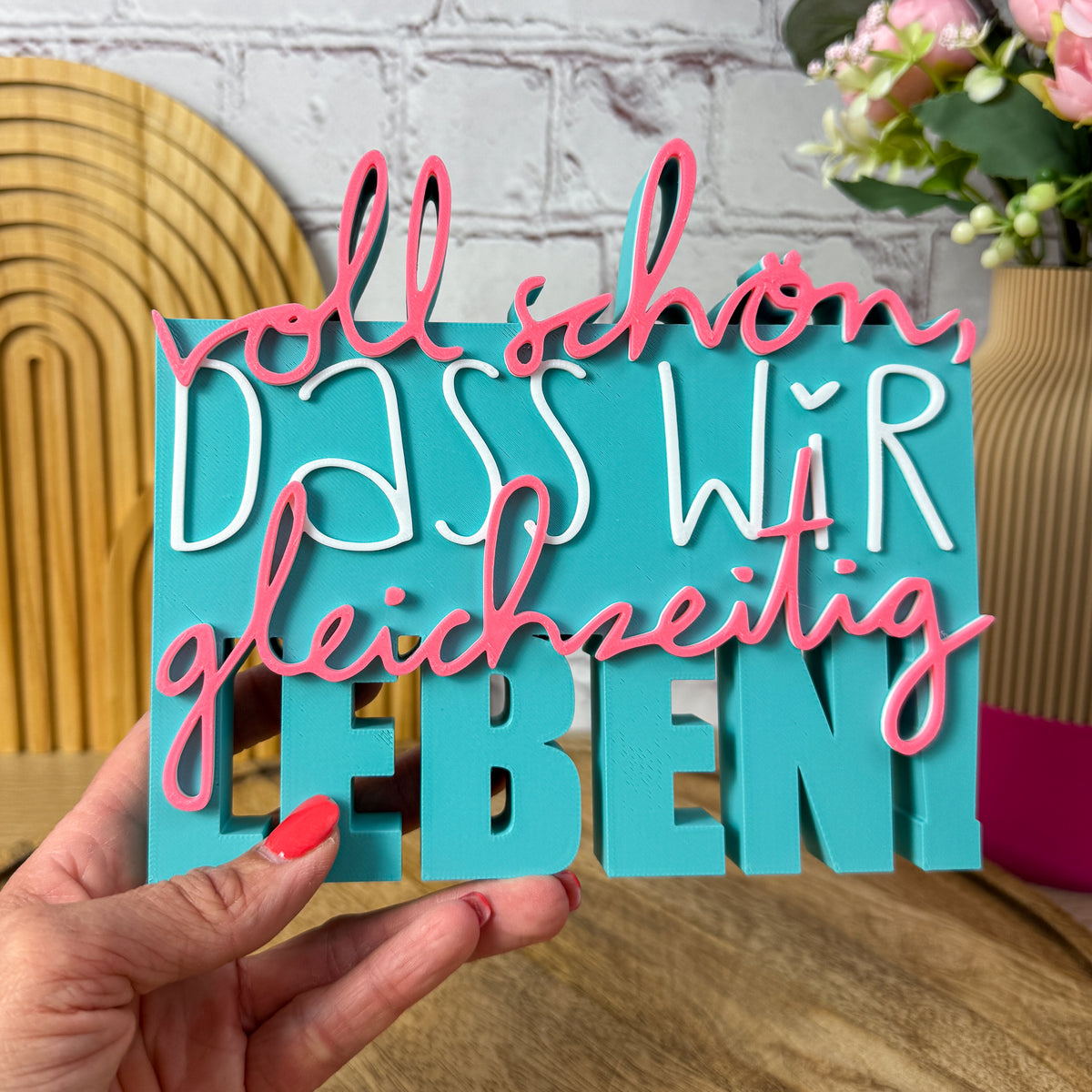 3D Spruch „Voll schön, dass wir gleichzeitig leben“ Größe 18 cm in Türkis, weiß und rosa, in einer Hand gehalten