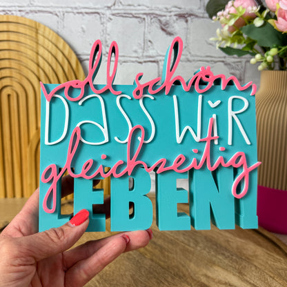 3D Spruch „Voll schön, dass wir gleichzeitig leben“ Größe 18 cm in Türkis, weiß und rosa, in einer Hand gehalten