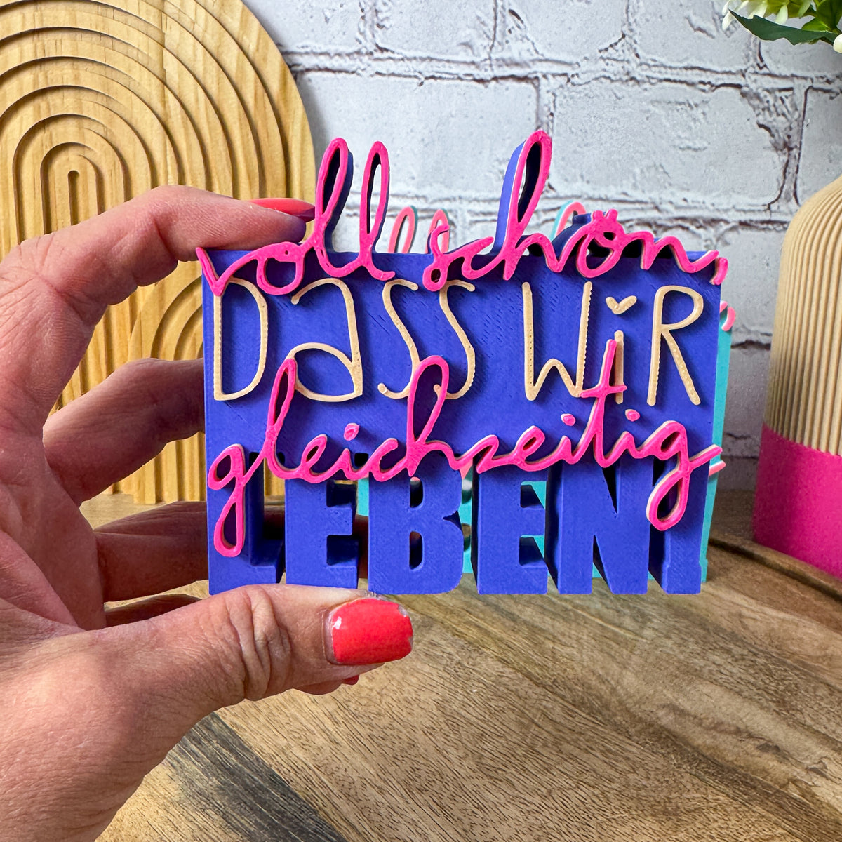 3D Spruch „Voll schön, dass wir gleichzeitig leben“ in lila, beige und magenta als Schild